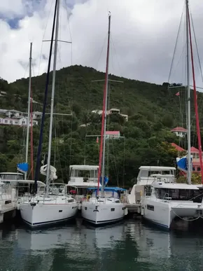 2020 Jeanneau Sun Odyssey 410 sailboats docked in a scenic marina with lush hillside backdrop.