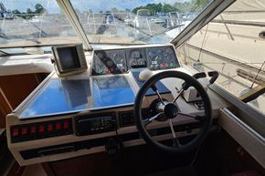 Control panel of a 1989 Princess 35 Flybridge yacht with steering wheel and navigation instruments.
