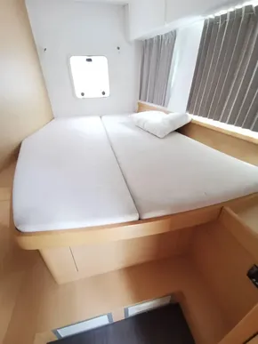 Interior cabin of a 2020 Lagoon 42 catamaran with a cozy bed and window.