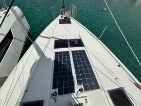 2019 Jeanneau Sun Odyssey 440 sailboat with solar panels on deck, docked in clear water.