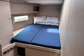2023 Beneteau Oceanis 51.1 cabin with blue mattress and wooden interior.