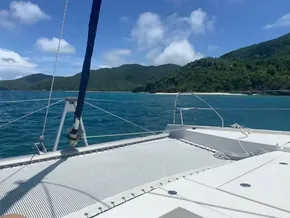 Leopard 40 catamaran sailing near lush green island, clear blue waters, and sunny skies.