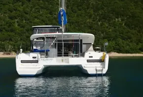 2020 Lagoon 42 catamaran anchored near lush green shoreline.