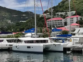 2020 Lagoon 42 catamaran docked in a scenic marina with hillside buildings.