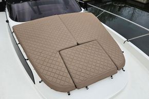 2023 Balt 818 Titanium boat with quilted tan deck cushions, docked by water.