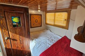 Cozy 1927 Classic Dutch Barge bedroom with wooden decor and stained glass door.
