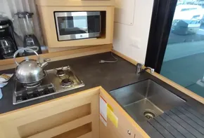 Modern kitchen in a 2020 Lagoon 42 yacht with stove, sink, and microwave.