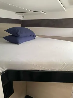 Modern yacht bedroom with white bedding and blue pillows, Leopard 50, 2020 model.
