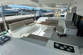 Spacious deck of 2020 Lagoon 46 catamaran with seating and table, docked at marina.