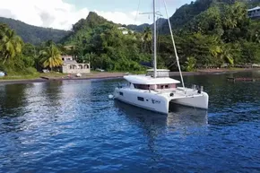 2024 Lagoon 42 catamaran anchored near lush tropical shoreline.