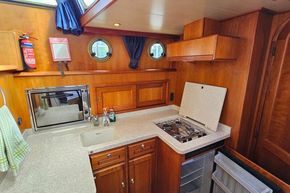 2005 Stevens 1200 Vlet boat kitchen with wooden cabinetry, stove, and porthole window.