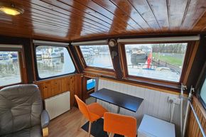 Interior of a 1921 Classic Dutch Barge with wooden paneling and river view.