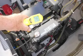 Hand using a yellow infrared thermometer on a Lagoon 42 engine, 2017 model.