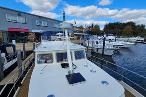 2005 Stevens 1200 Vlet docked at marina, clear sky, modern building in background.