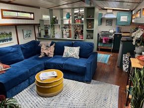 Interior of a 1901 Classic Dutch Barge with cozy blue sofa and modern kitchen.