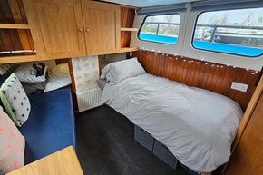 Cozy interior of a 1921 Classic Dutch Barge with wooden paneling and comfortable bedding.