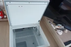 Open freezer compartment on 2024 Lagoon 42 yacht, with wooden countertop and decorative seashells.