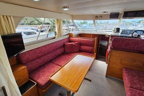 Interior of 1989 Princess 35 Flybridge yacht with red seating and wooden table.