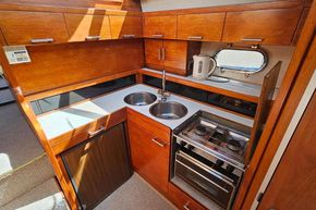 Compact kitchen in 1989 Princess 35 Flybridge yacht with wood cabinetry and modern appliances.