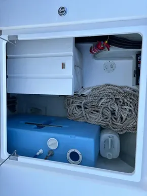 Storage compartment of a 2019 Leopard 40 boat with rope, fire extinguisher, and blue tank.