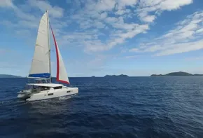 Lagoon 42 catamaran sailing in open sea, 2020 model, under a partly cloudy sky.
