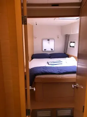 Cozy bedroom in 2020 Lagoon 42 catamaran with double bed and porthole windows.