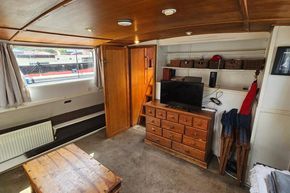 Interior of a 1926 Dutch Barge Luxemotor with wooden furniture and a TV.