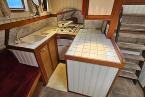 Cozy 1926 Dutch Barge Luxemotor kitchen with vintage sink, stove, and wooden cabinetry.
