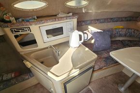 1999 Wellcraft 2400 Martinique cabin interior with kitchenette and seating area.