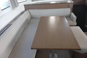 Interior seating area of a 2020 Lagoon 46 catamaran with wooden table and white cushions.
