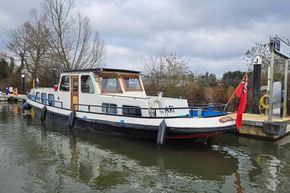 Classic 1921 Dutch Barge moored at a dock, featuring a red flag and serene surroundings.