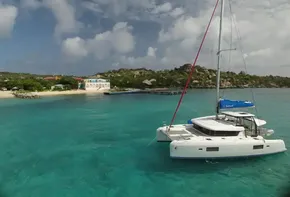 Lagoon 42 catamaran 2020 anchored in clear turquoise waters near a scenic coastline.