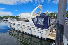 1989 Princess 35 Flybridge yacht docked at marina, featuring blue canopy and fenders.