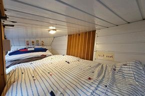 Cozy bedroom interior of a 1921 Classic Dutch Barge with nautical-themed bedding.