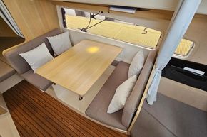 Cozy interior of 2023 Balt 818 Titanium boat with wooden table and cushioned seating.