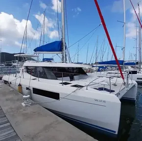 2019 Leopard 45 catamaran docked at marina with blue sails.