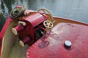 Red and cream 1927 Classic Dutch Barge steering wheel and deck by the water.