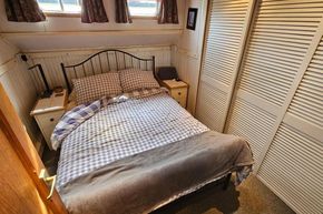 Cozy bedroom in a 1926 Dutch Barge Luxemotor with checkered bedding and wooden accents.