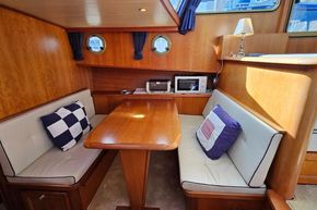 Cozy dining area in 2005 Stevens 1200 Vlet boat with wooden table and cushioned seating.