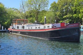 Luxemotor Dutch barge from 1926, named Alpha-Wilja, docked on a sunny day.