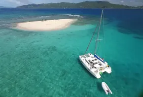Lagoon 42 catamaran (2020) anchored near a small tropical island in clear turquoise waters.