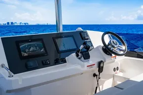 Helm of 2025 Leopard 40 Powercat with navigation screens, steering wheel, and ocean view.