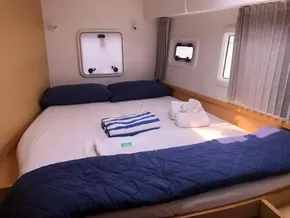 Cozy bedroom in 2020 Lagoon 42 catamaran with neatly arranged bed and windows.