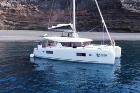 2024 Lagoon 42 catamaran anchored near rocky shoreline, calm blue waters.