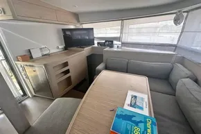 Interior of 2024 Lagoon 42 yacht with modern seating, table, and TV.