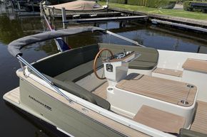 2026 Enkhuizensloep 680 Tender boat with sleek design and wooden accents docked by the water.