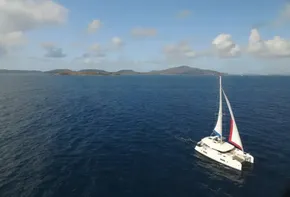 Lagoon 42 catamaran sailing in open sea, 2020 model, with distant islands and blue sky.