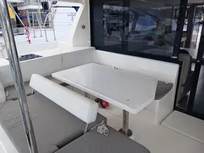 Outdoor seating area on a 2021 Leopard 40 catamaran with a white table and cushioned benches.