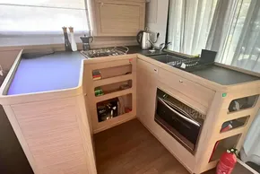 Modern kitchen in 2024 Lagoon 42 yacht with stove, oven, and sleek cabinetry.