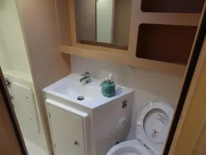Modern bathroom in a 2020 Lagoon 42 catamaran with sink, toilet, and storage shelves.